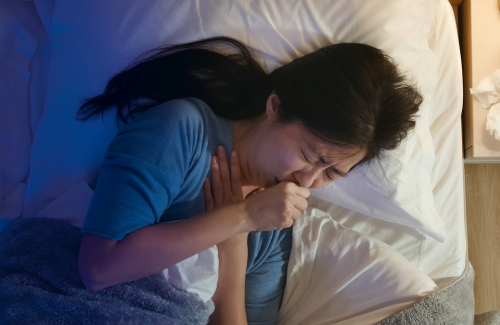 ベッドで咳き込む女性