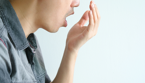 口元に手を当てる男性