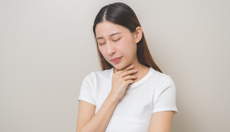 喉に手を当てる女性